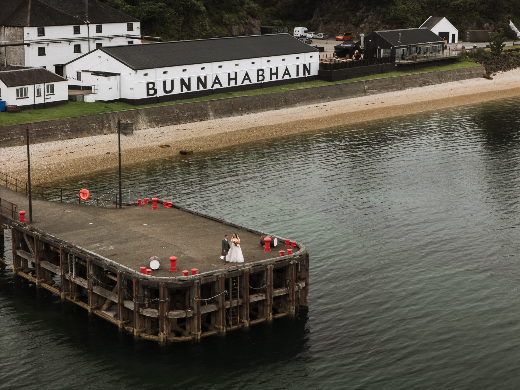 a pier surround by water and a whiskey distillery in the background