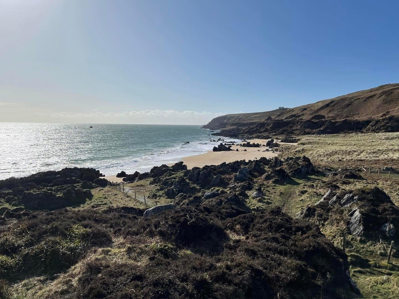 Image showing a rocky shoreline with waves and cliffs in the background with a sunny sky
