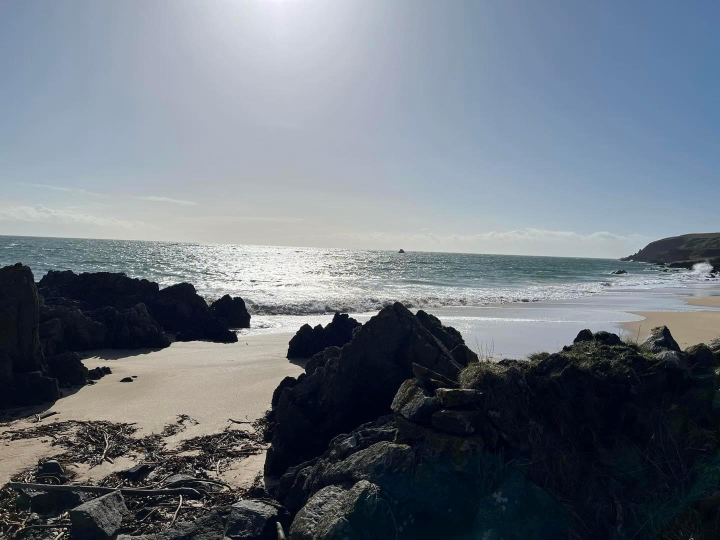 image showing a rocky shoreline with a water in blue sky in the background