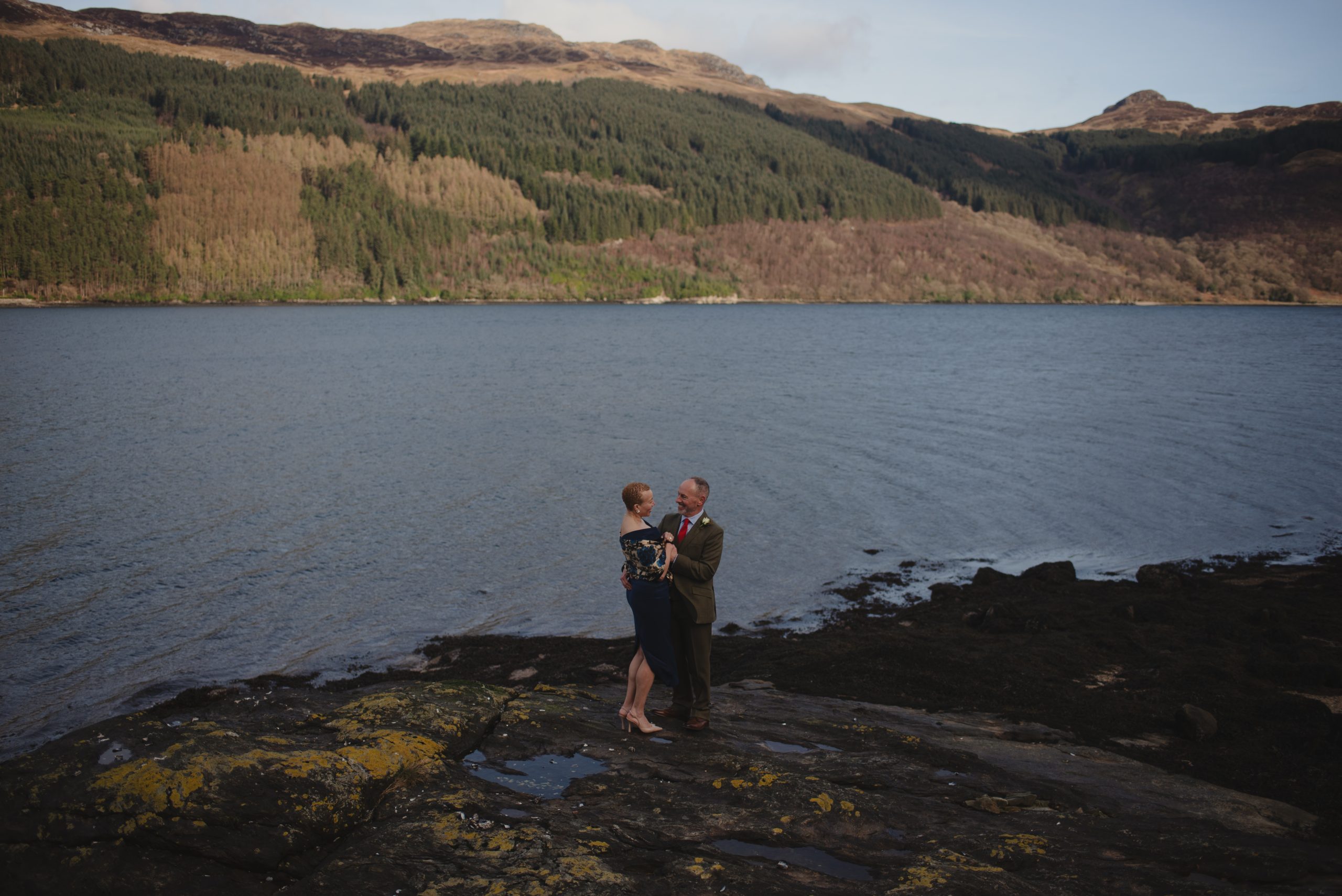 a man and woman on a cliff overlooking water