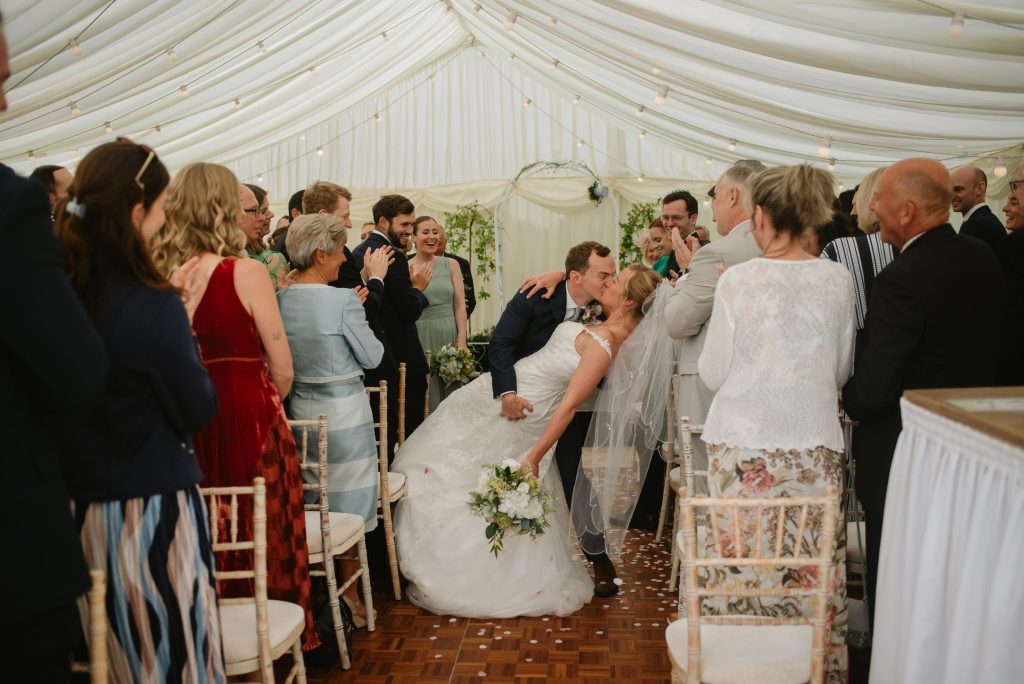 marquee with lots of people man and woman in aisle kissing
