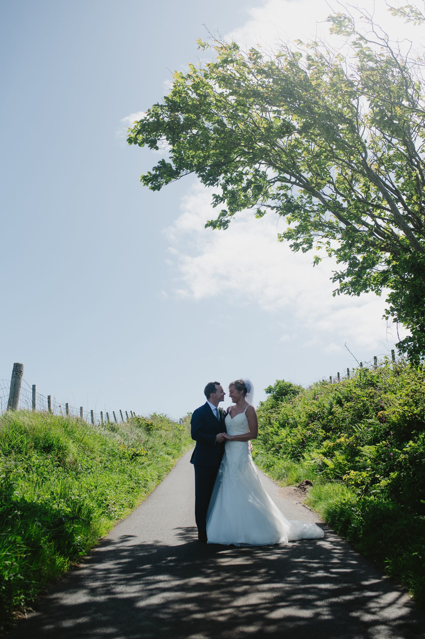 woman in white dress with man in suit in the middle of road blue skies behind
