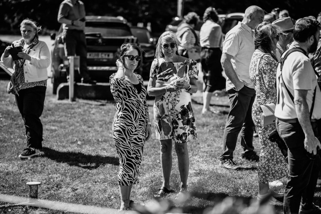 2 woman in dresses standing in a crowd of people
