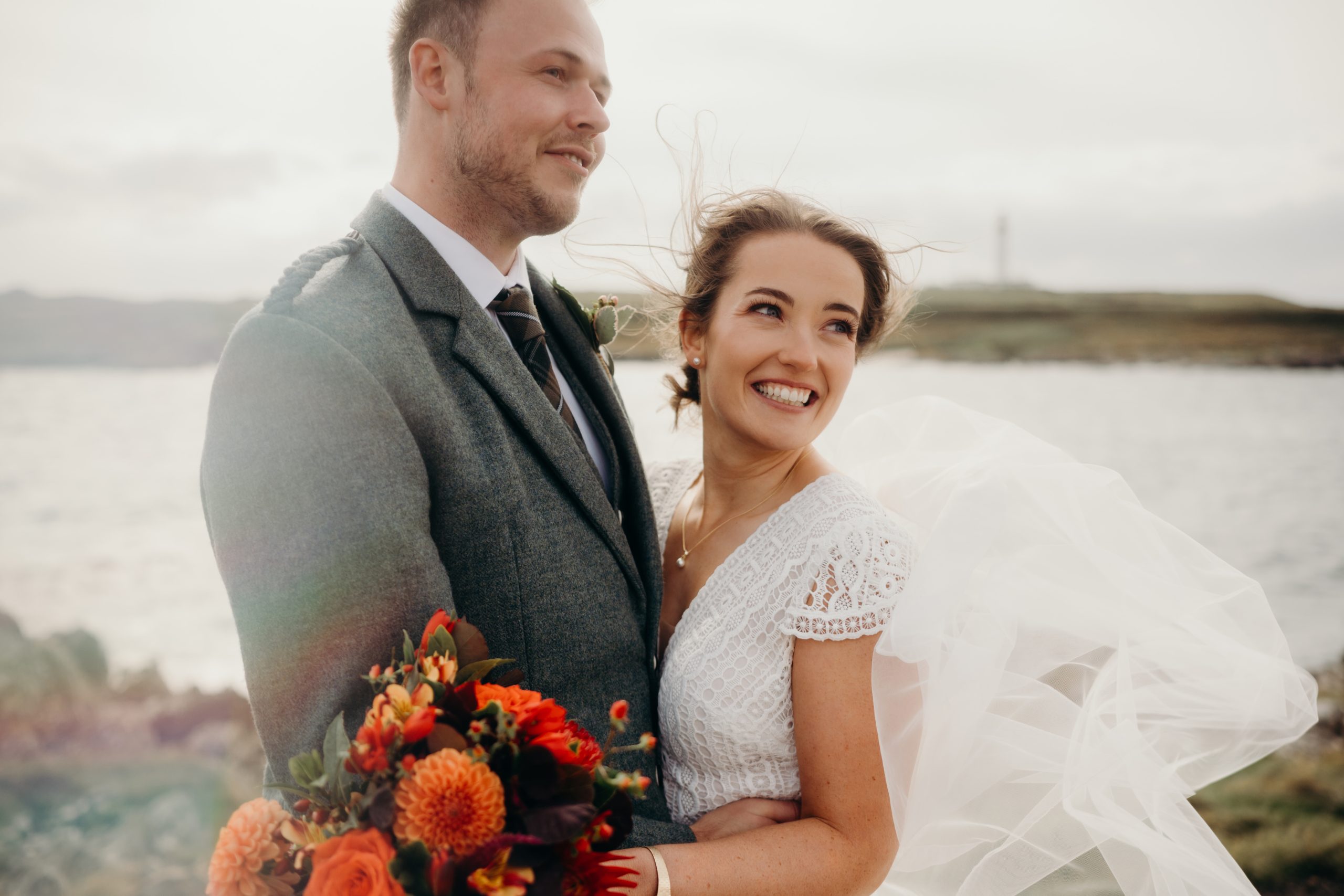 Man in grey jacket with woman in white dress hugging