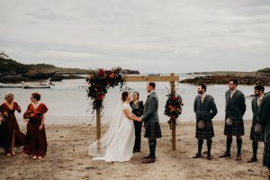 a group of people on the beach - Bride and groom in the middle water in the background