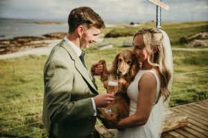 man holding champagne glass next to woman holding a puppy dog