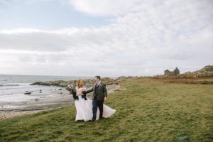 Man and woman walking along grass by beach