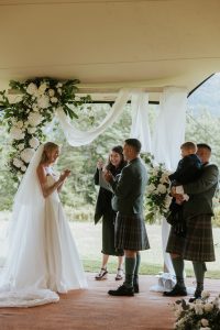 under a tent woman in white dress and man in kilt