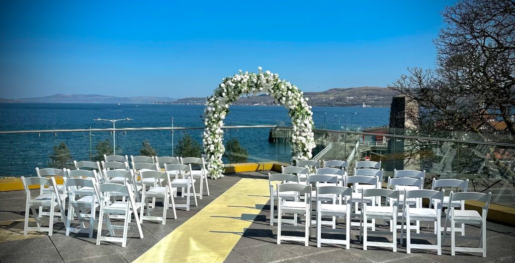 image showingchairs set up for a wedding ceremony on an outdoor terrace