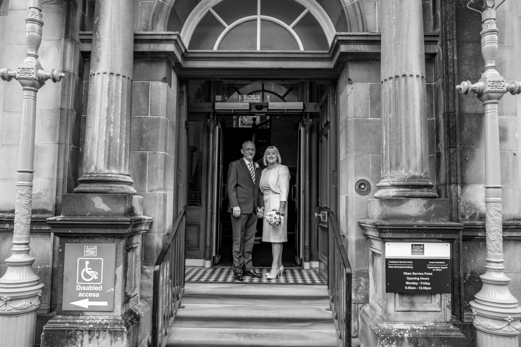 black and white photo of a man and woman standing of the steps of an old building