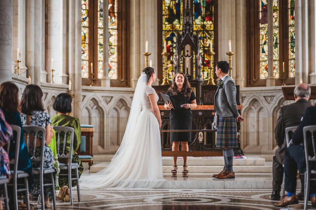 A marble chapel with a woman in white dress woman in black dress and a man in a grey kilt