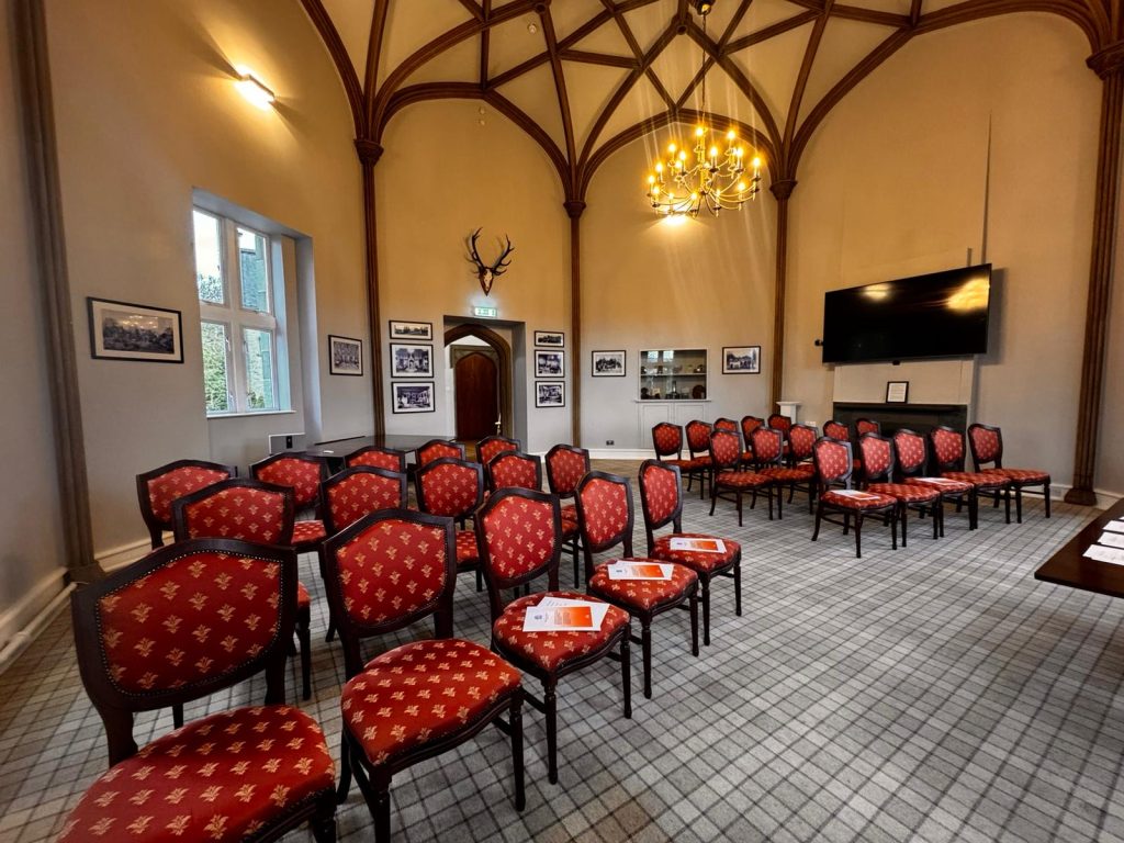 A room with dark red chairs with a tartan carpet