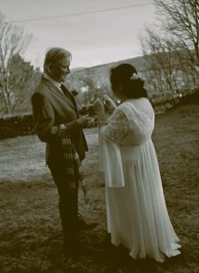 Black and White photo woman wearing a dress holding a quaich next to a man in a suit