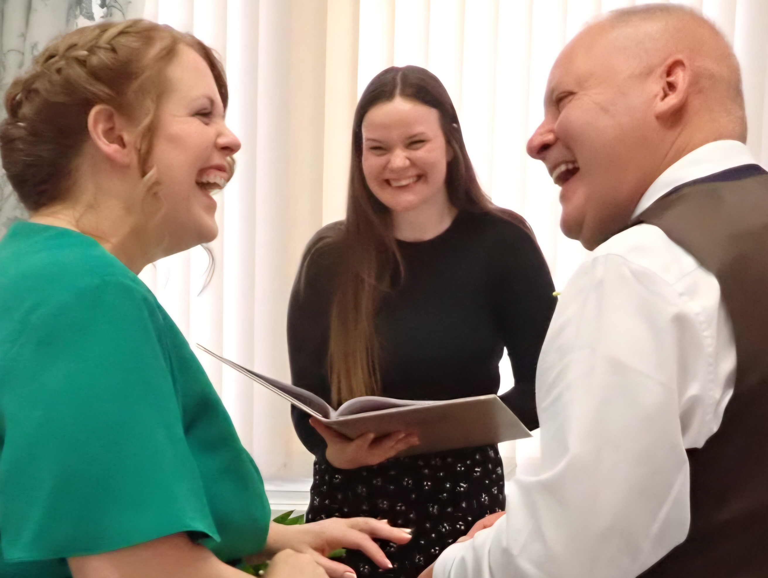 a man and woman looking at each other smiling with a Registrar in the middle laughing