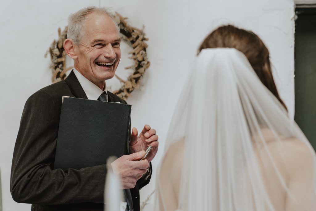 Man in suit smiling next to a bride with veil