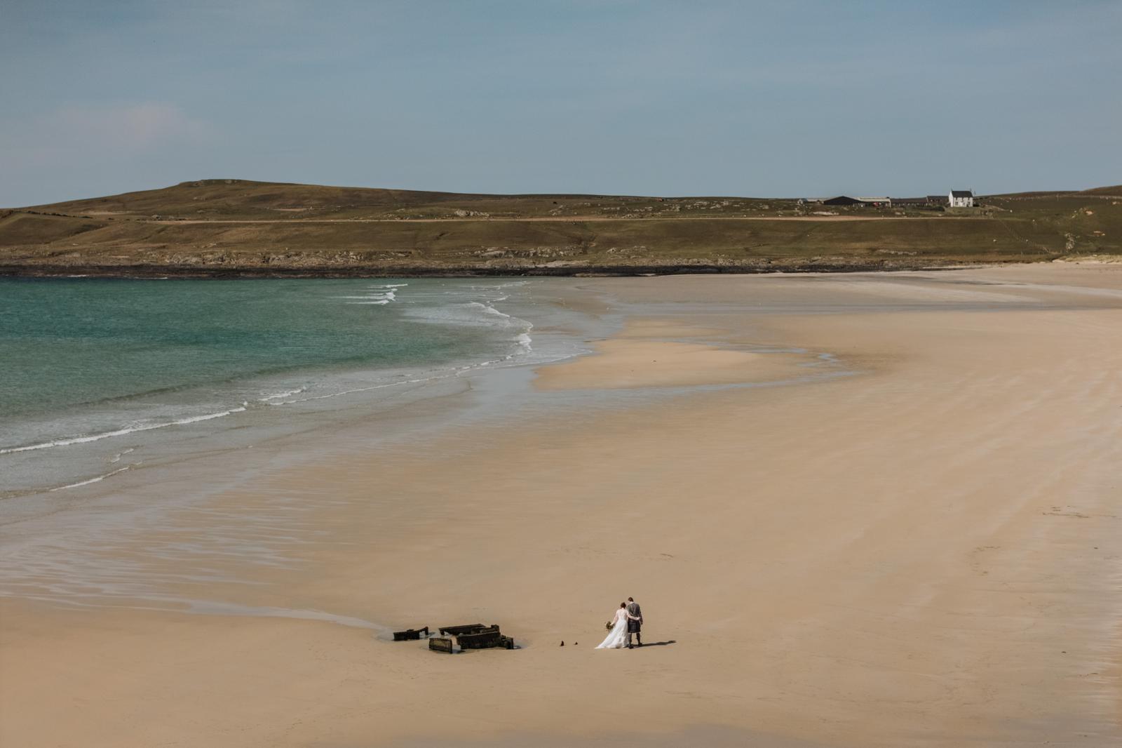 a beach with 2 people walking across it