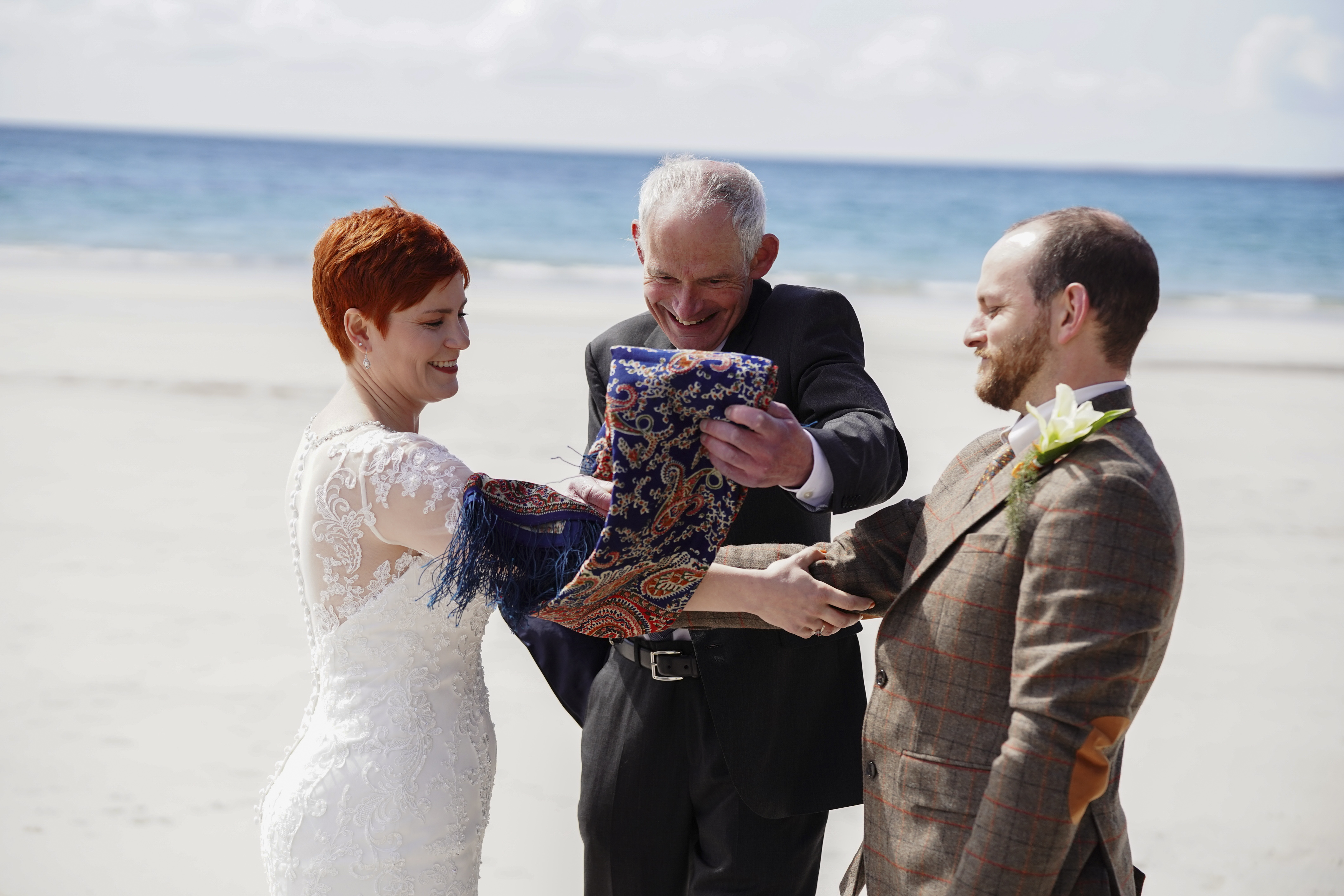 3 people 2 holding hands while a man wraps their hands with material
