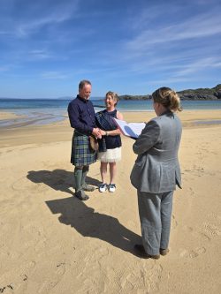 2 woman and 1 man standing on a beach blue sky