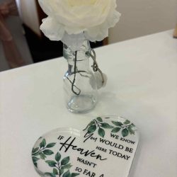 a table with a white flower and a heart with wording on it.