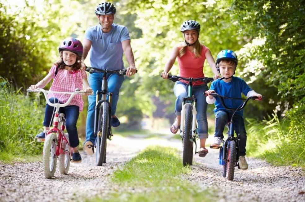 Images shows two adults and two children cycling down a track