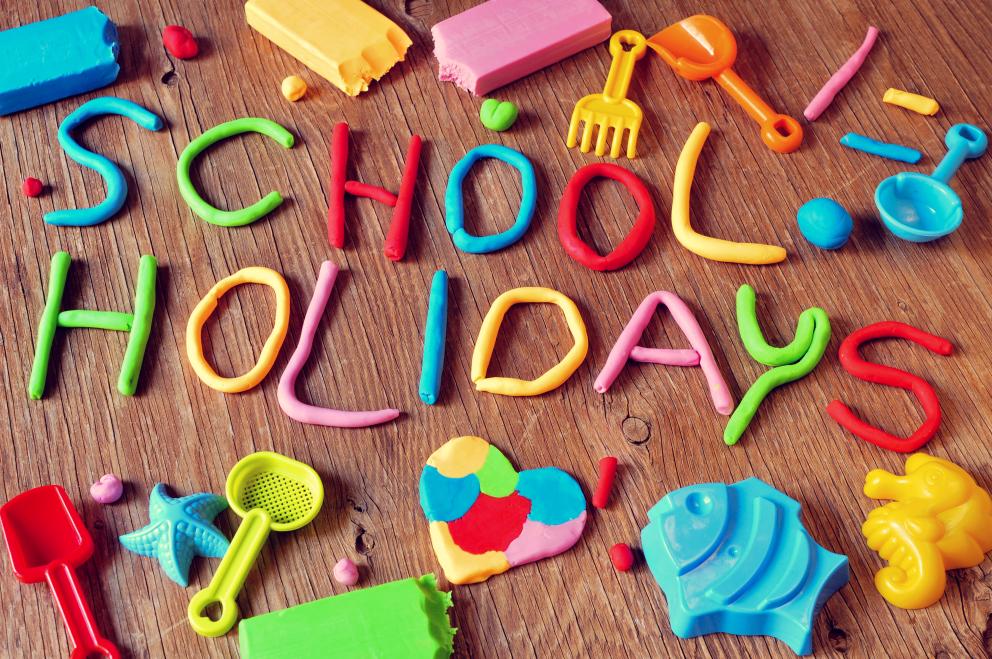 Images shows the words school holidays made of brightly coloured clay