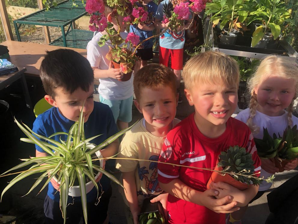 Pupils holding plants in the new greenhouse