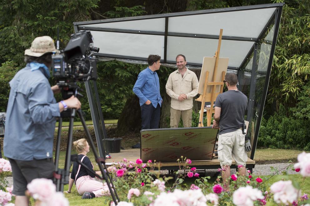 Image shows a camera filming two presenters