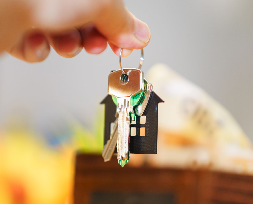 a hand holding a keyring with a house on it