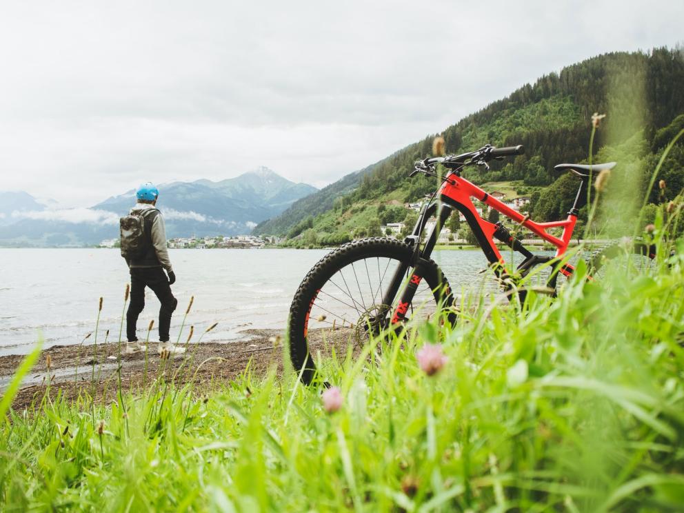 Image shows a bike in the foreground with a person looking out to the water in the background