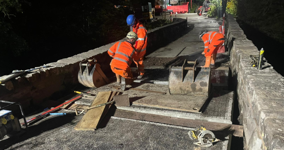 Three workers on bridge fitting new slab