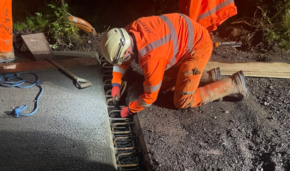 A worker on his hands and knees, installing slabs on the bridge.