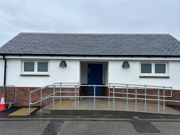Single story toilet block building from front with ramp leading to main door at centre
