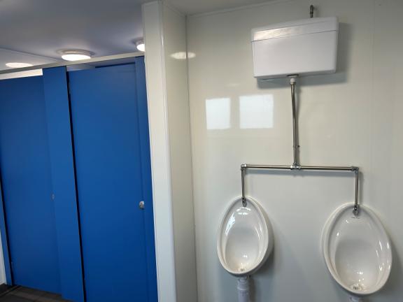 Two urinals and two cubicles alone a wall