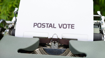 a typewriter with paper in it with the words postal vote