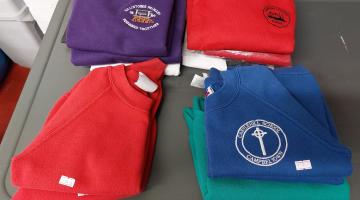 Images shows folded  red and blue school jumpers