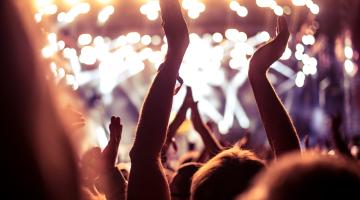 View towards stage of crowd with hands up at a festival 