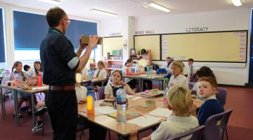 Image shows pupils  back in their classroom with their teacher 