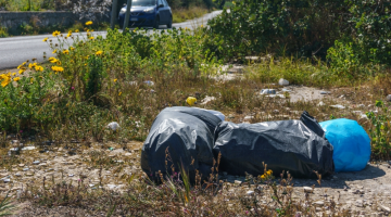 black plastic bags of rubbish lying at the side of the road