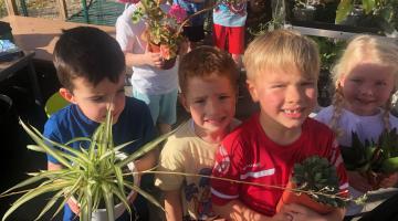 Pupils holding plants in the new greenhouse