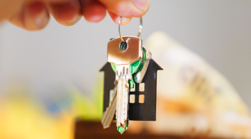 a hand holding a keyring with a house on it