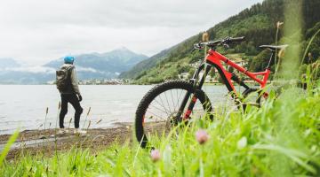 Image shows a bike in the foreground with a person looking out to the water in the background