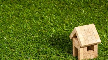 small wooden house on green grass backdrop