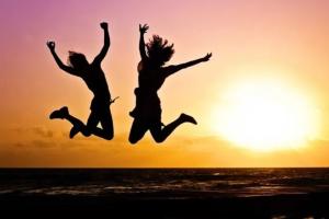 Image shows two young people jumping into the air celebrating 