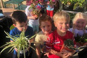 Pupils holding plants in the new greenhouse