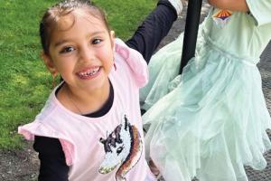 Image shows two girls, one on a rope swing smiling 