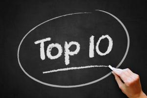 Image shows a hand writing on a blackboard the words top ten