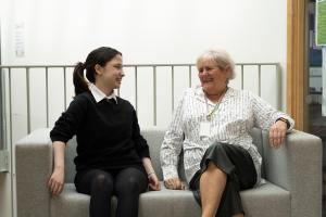 A young girl sits next to her female mentor 