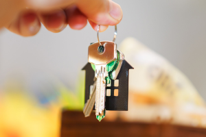a hand holding a keyring with a house on it