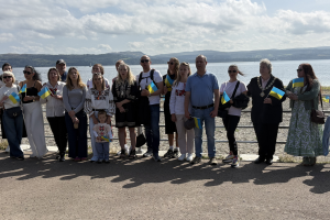 A group of people stand in front of the railings at the sea front in Dunoon
