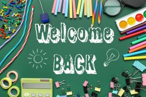 Image shows a green welcome back sign with different bits of stationery around the sides including pencils and paint